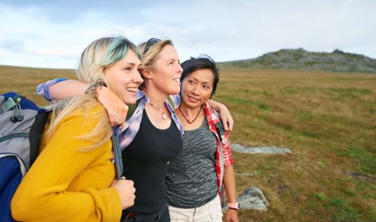 A group of hiking friends huddle together on a rocky moorland in an idyllic rural countryside.